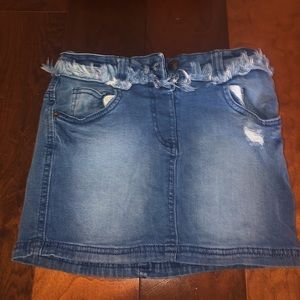 Girls denim skirt with loose threads.